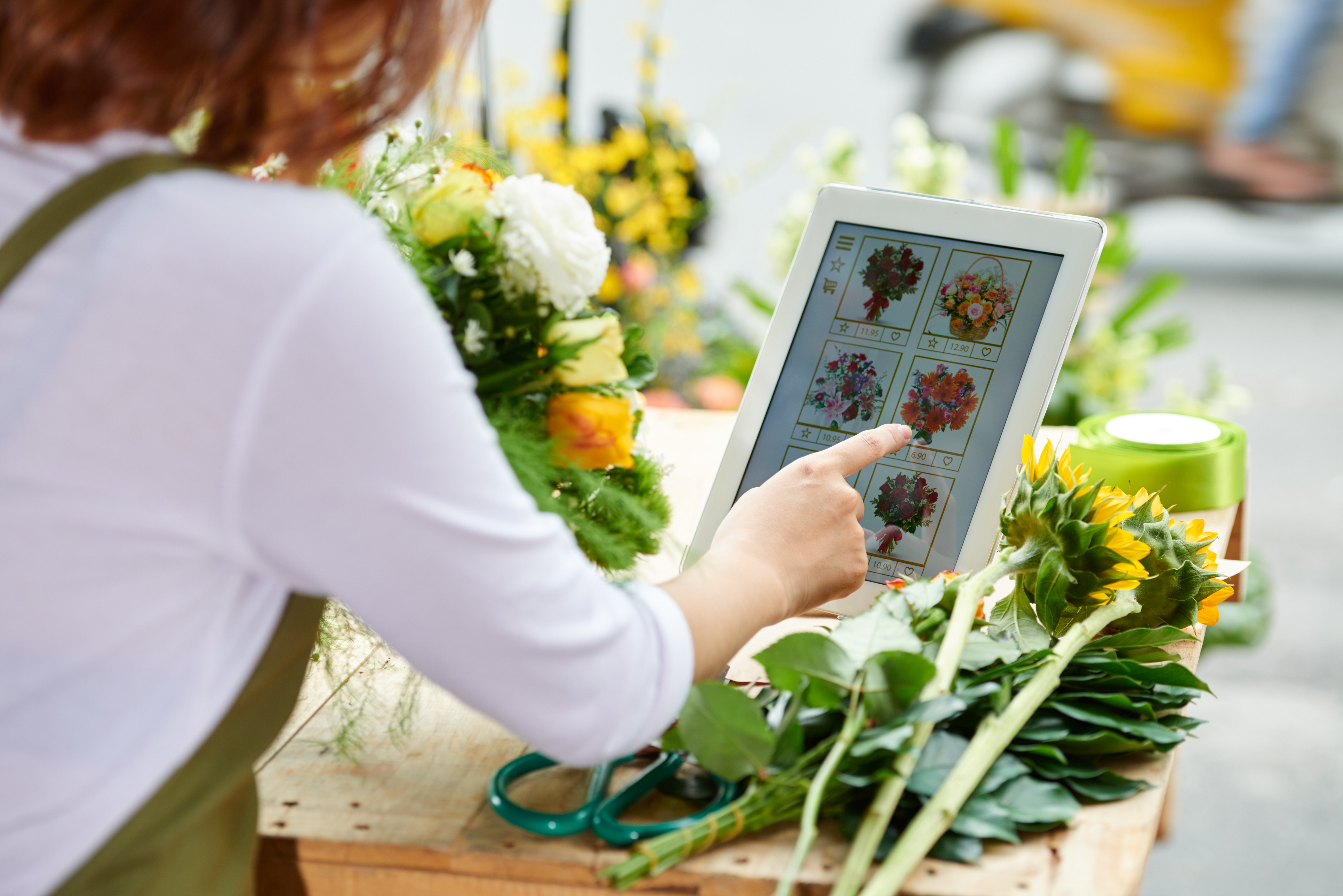 Florist picking flowers arrangements on her tablet screen.